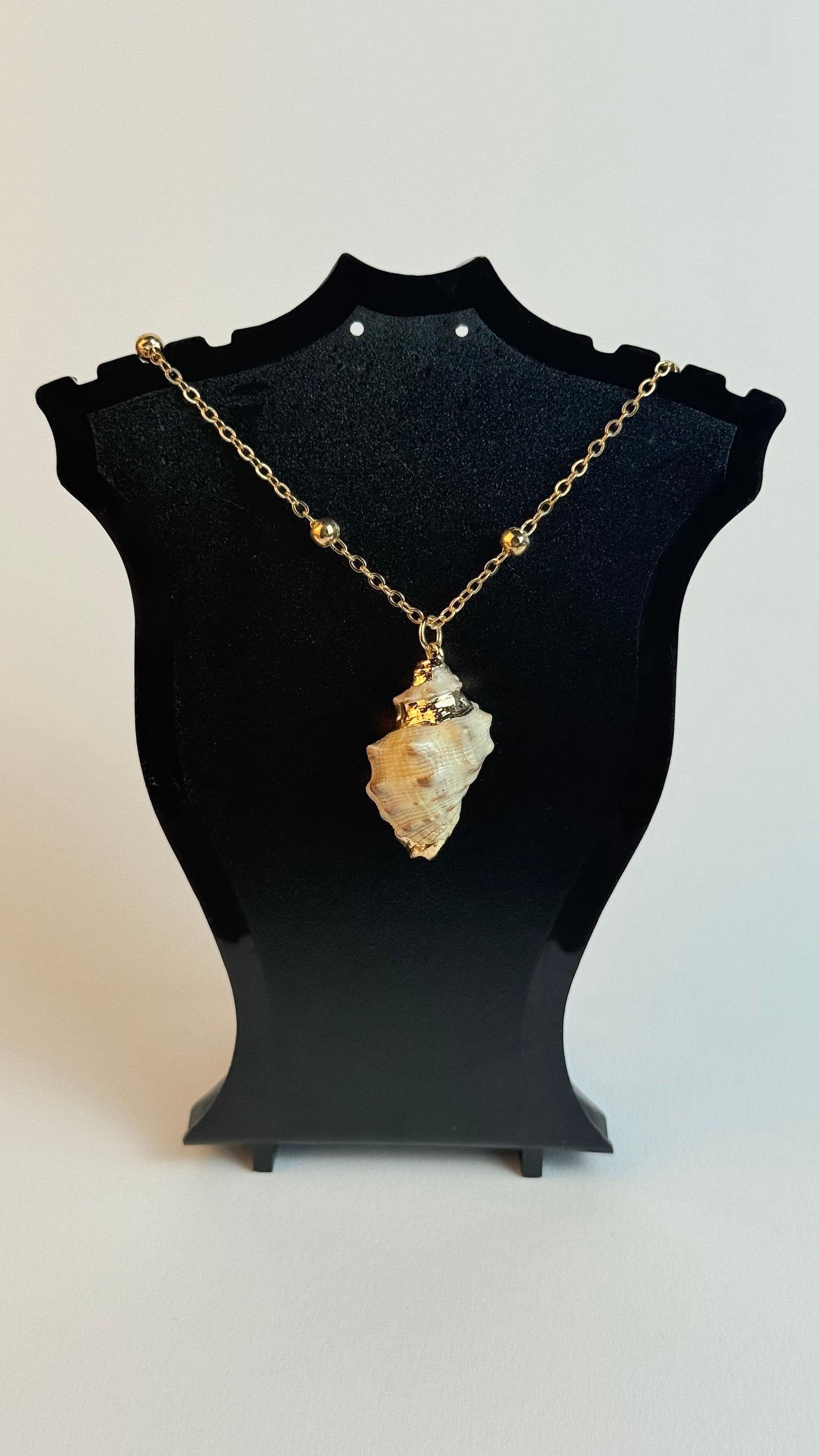 Necklace with a stone pendant on a black bust against a white background