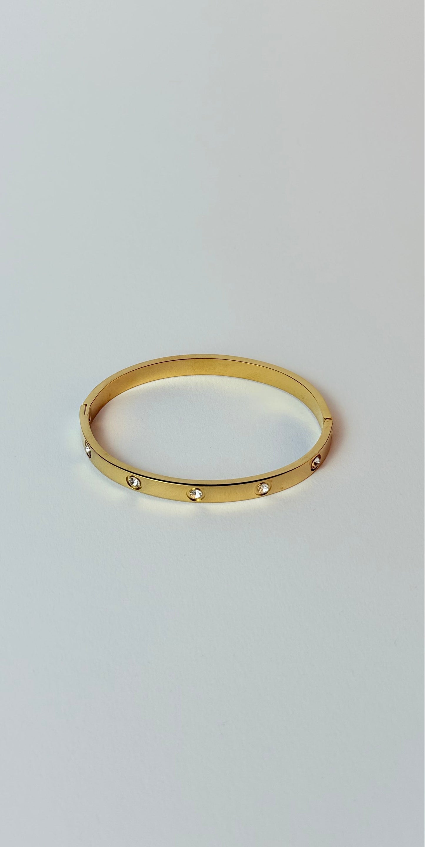 Gold ring with small stones on a light gray background