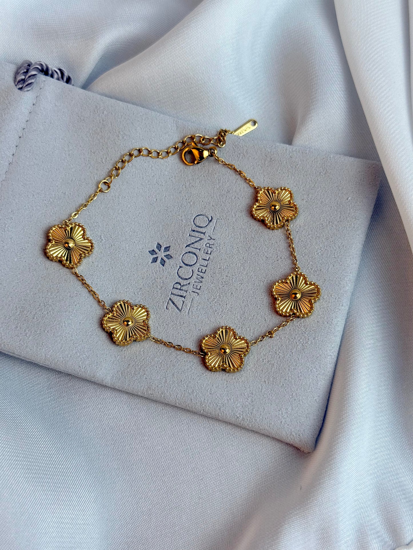 Gold floral bracelet on a ZirconiQ jewelry box with a white fabric background