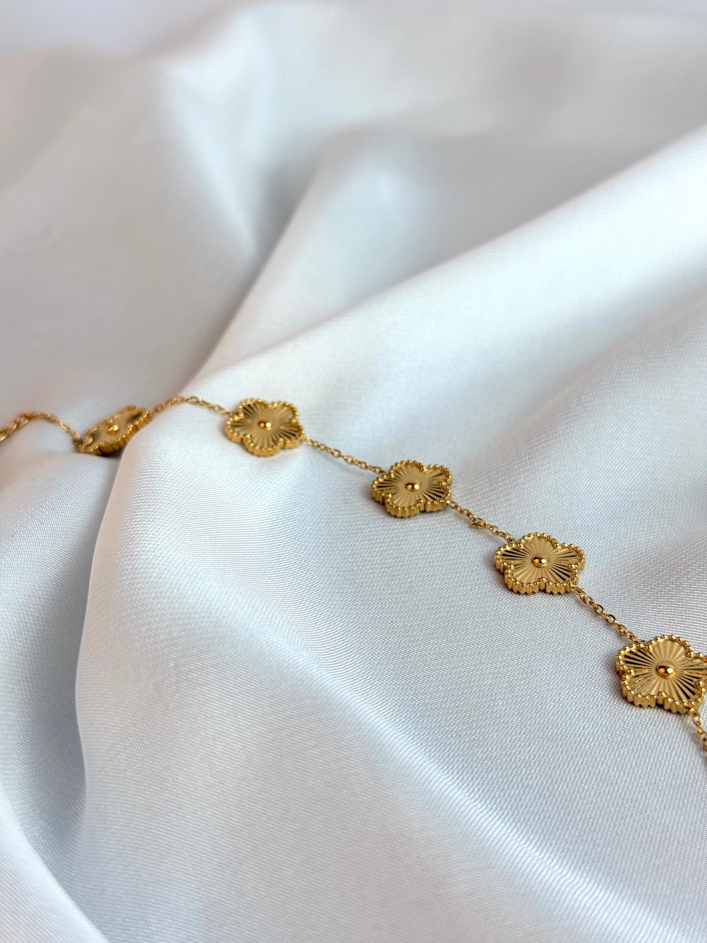 Gold bracelet with floral designs on a white fabric background