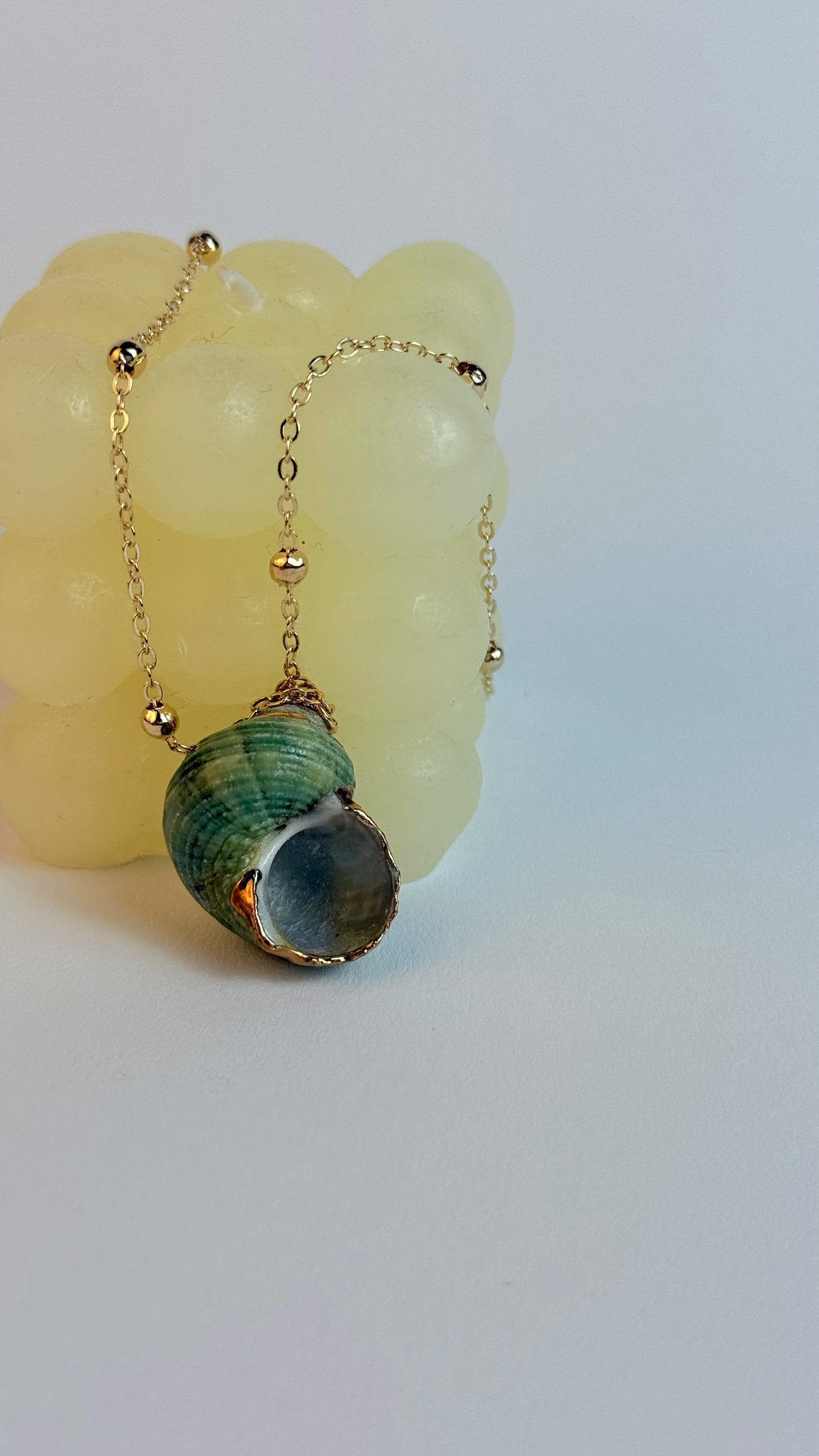 Necklace with a green and gray pendant on a white background