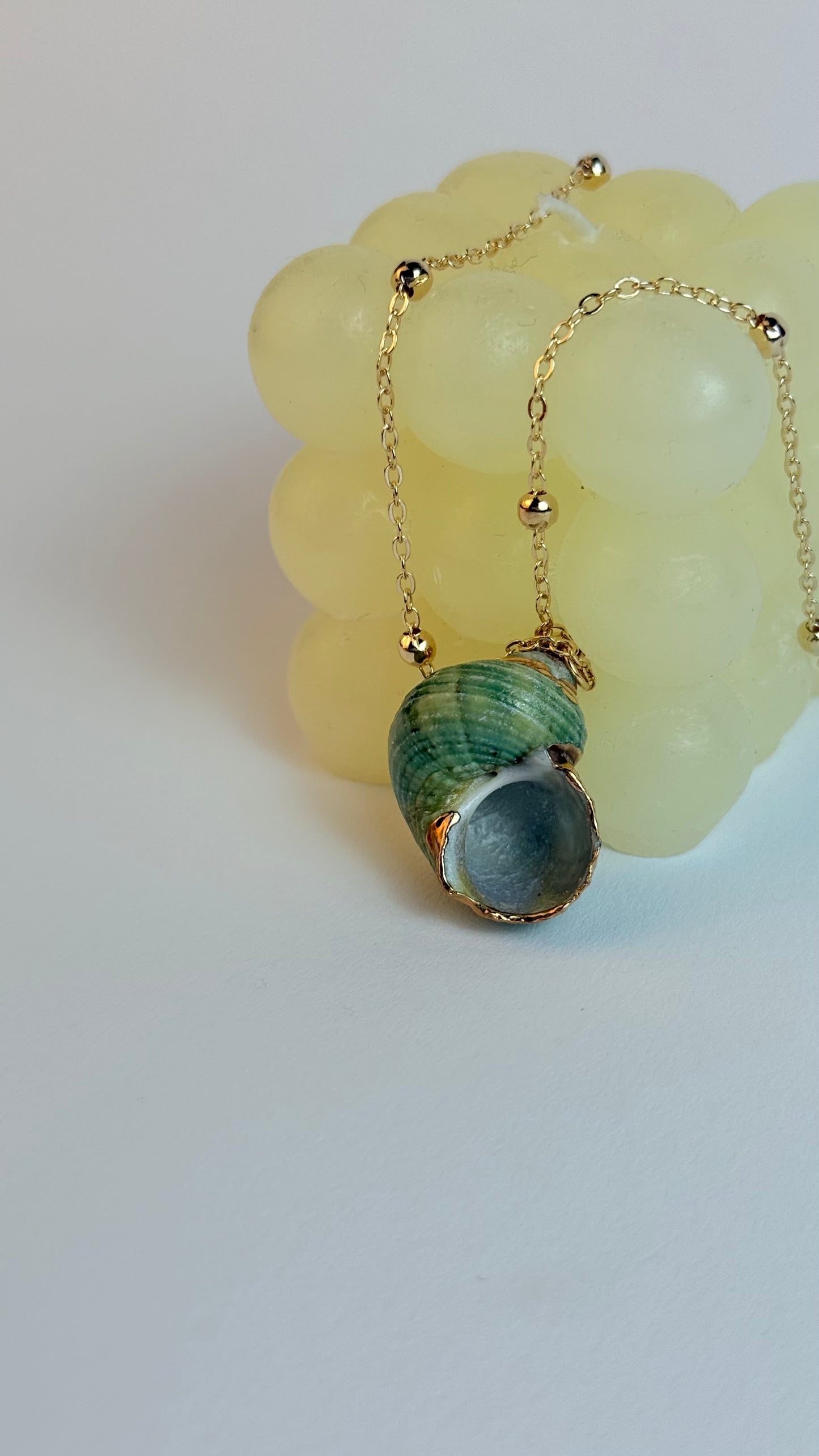 Necklace with a green shell pendant on a light background