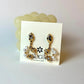 Pair of gold and pearl earrings on a display card with a visible brand logo.