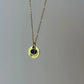 Gold necklace with a round pendant featuring a blue gemstone on a gray background
