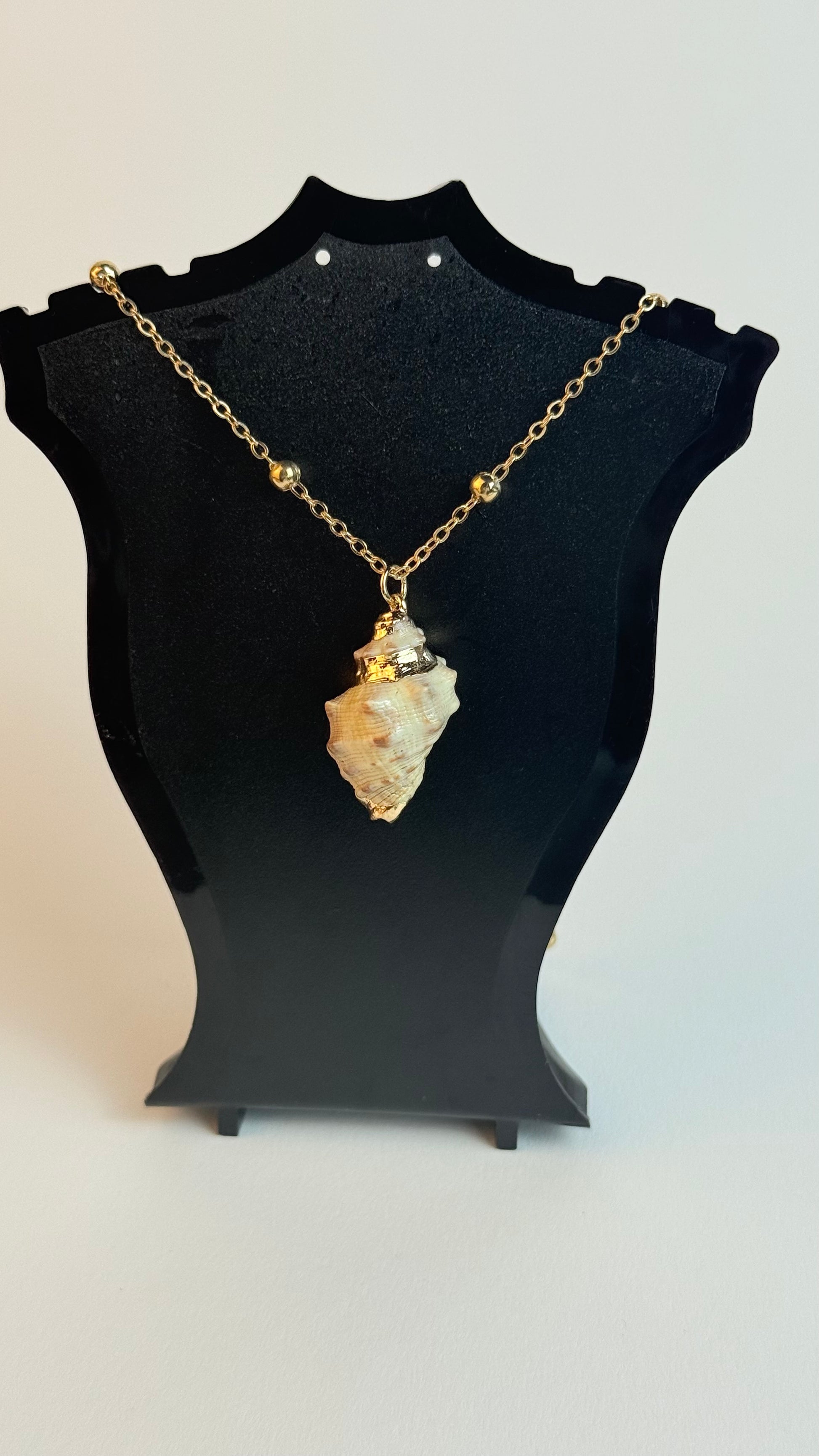 Necklace with a stone pendant on a black stand against a white background