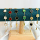 Set of colorful flower-shaped bracelets on a green cushion with a white background
