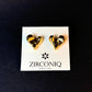 Heart-shaped gold earrings on a Zirconiq branded card against a black background