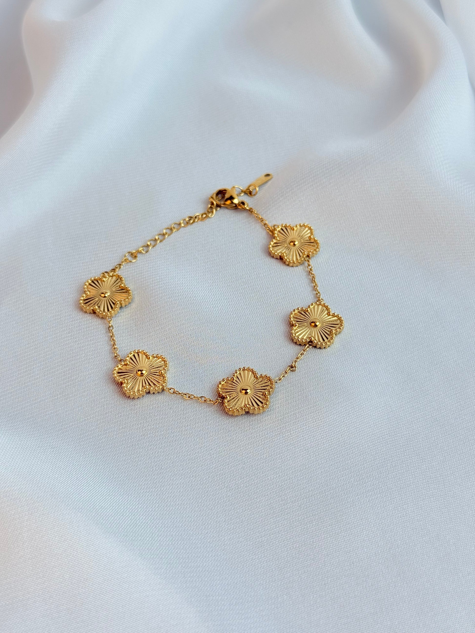 Gold bracelet with floral designs on a white fabric background