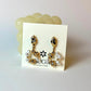 Pair of gold and pearl earrings on a display card with a visible brand logo.