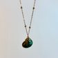 Necklace with a green shell pendant on a light gray background