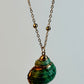 Necklace with a green shell pendant on a light gray background