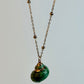 Necklace with a green shell pendant on a light gray background