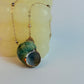 Necklace with a green and gray pendant on a white background