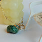 Green shell pendant on a gold chain with a white background