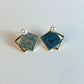 Pair of square earrings with blue centers and gold borders on a white background