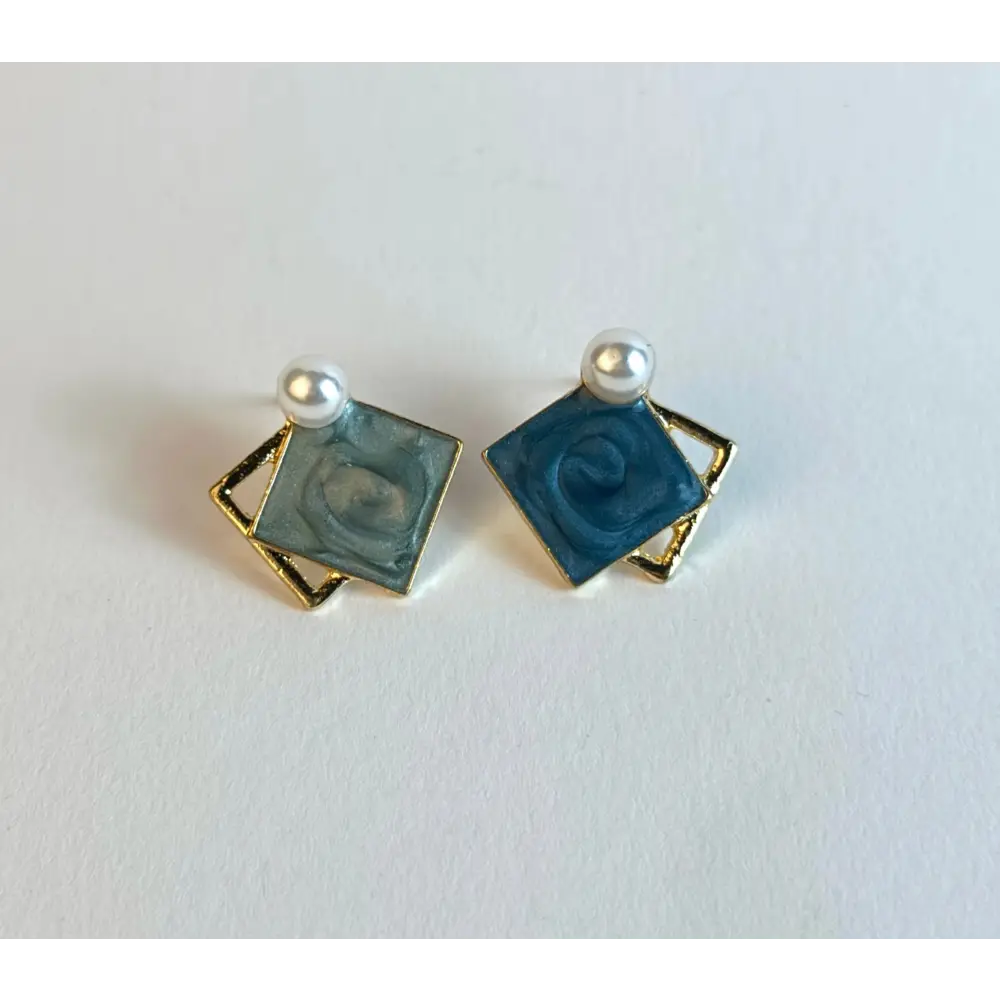 Pair of square earrings with blue centers and gold borders on a white background