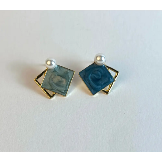 Pair of square earrings with blue centers and gold borders on a white background