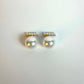 Pair of pearl earrings with gold accents on a white background