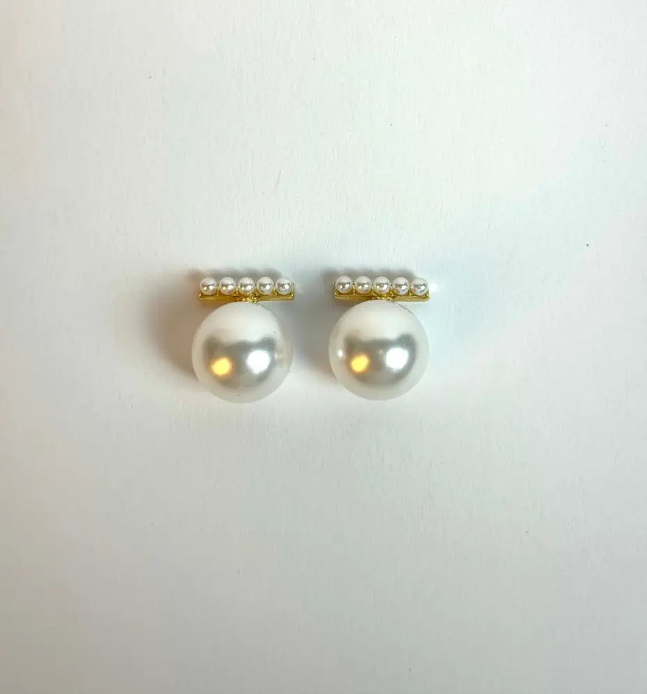 Pair of pearl earrings with gold accents on a white background