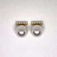 Pair of pearl earrings on a textured white background