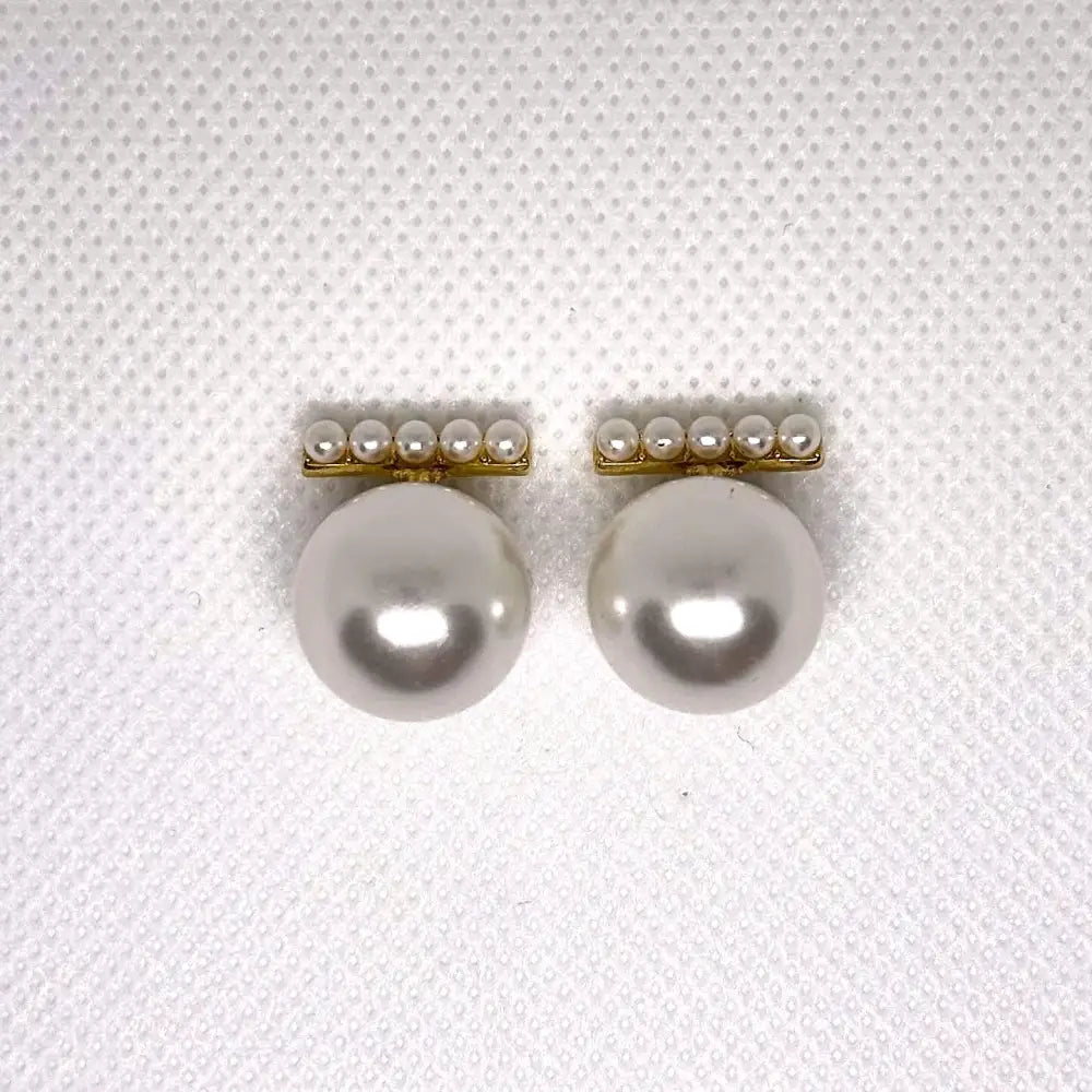 Pair of pearl earrings on a textured white background