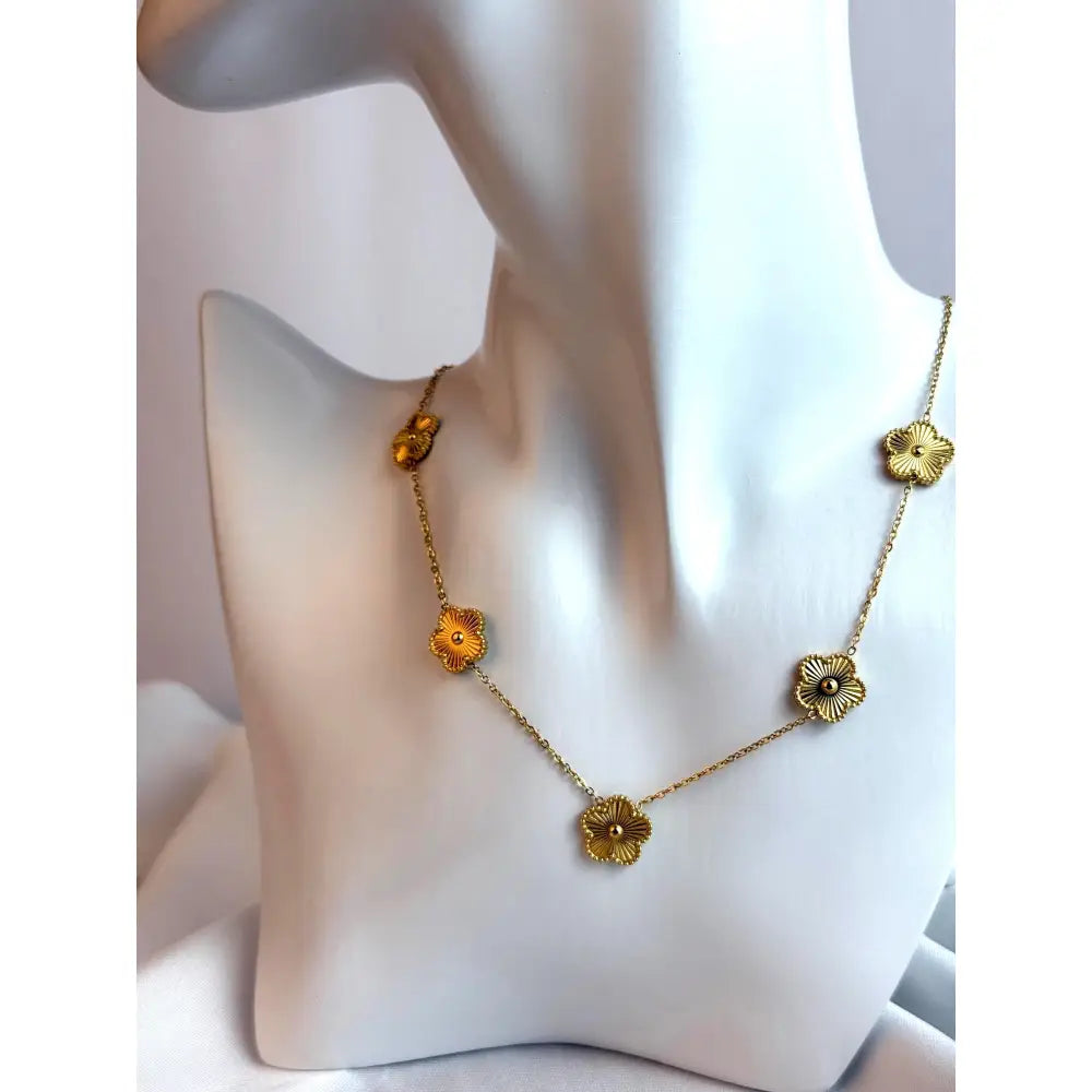 Gold necklace with floral designs on a mannequin bust.