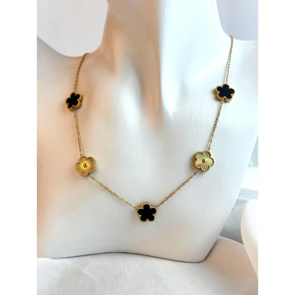 Gold necklace with black flower pendants on a mannequin bust.