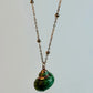 Necklace with a green shell pendant on a light gray background